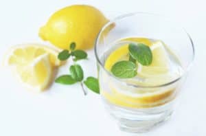 glass of water with a fresh slice lemon and mint spigs