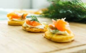 Low-Carb Smoked Salmon Blinis on a wooden board with dill in background
