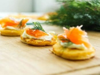 Low-Carb Smoked Salmon Blinis on a wooden board with dill in background