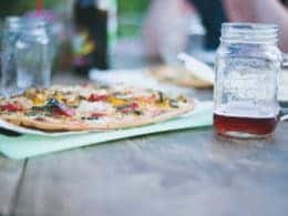 Cauliflower pizza on a table with a drink in a mason jar
