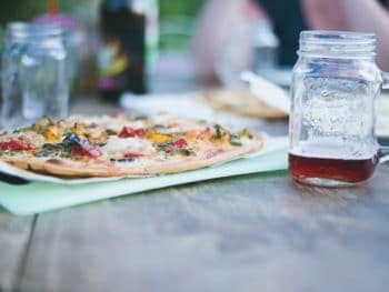 Cauliflower pizza on a table with a drink in a mason jar