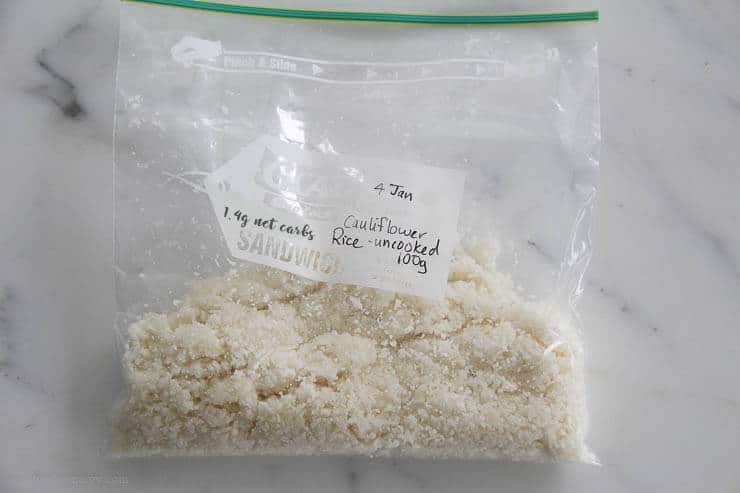 Frozen cauliflower rice in a zip-lock bag labelled with "100g uncooked cauliflower rice 1.4g carbs"