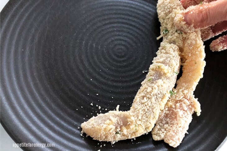 Place a piece of crumbed fish on plate ready for cooking