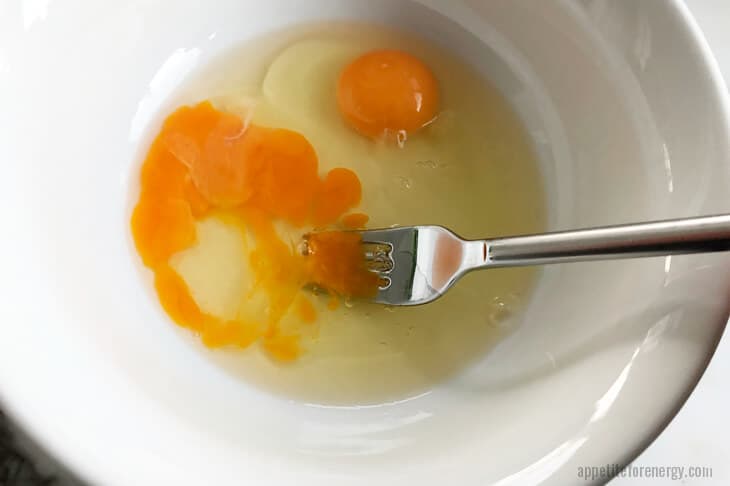 Whisking eggs lightly with fork in a white bowl