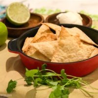 Low-Carb Tortilla Chips in a red bowl with lime, sour cream and cilantro