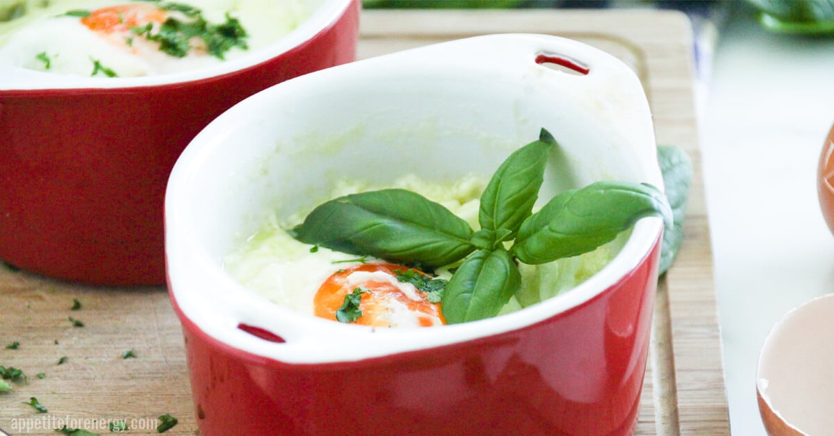 Baked eggs in a red ramekin with basil on top