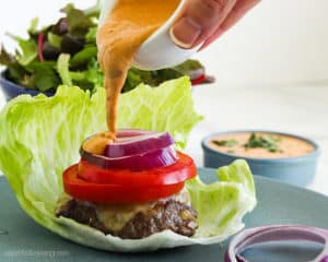 Pouring Chipotle Mayo from bowl onto a Low-Carb Burger