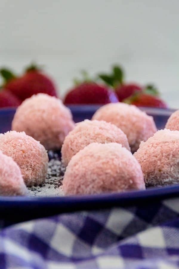 Low-Carb Strawberry Cheesecake Energy Balls on a plate with fresh strawberries