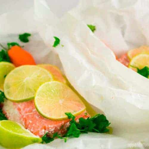 Chili Lime Oven Baked Salmon in the parchment paper that it cooks in, with fresh lime