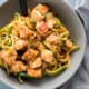 Crispy Pork LO Mein with Zoodles in a light grey bowl with a grey napkin and black spoon