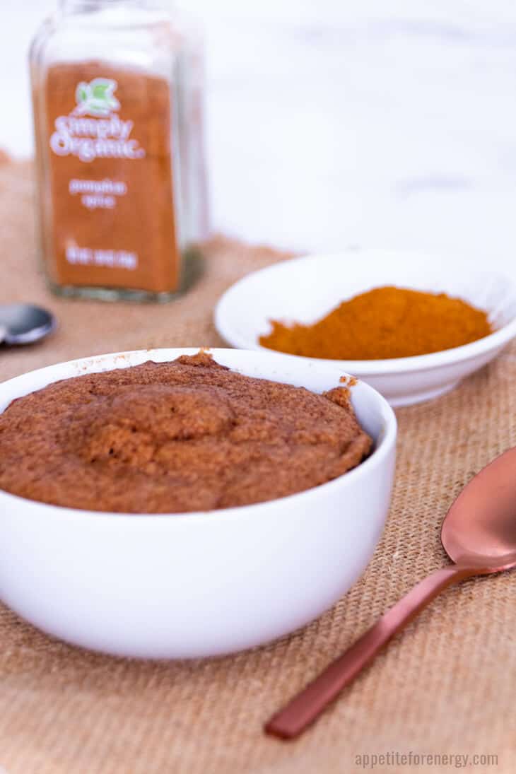 Pumpkin Spice Keto Mug Cake with the bottle of pumpkin spice in background