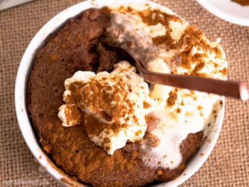 Overhead shot of a spoon digging in to Pumpkin Spice Keto Mug Cake with cream