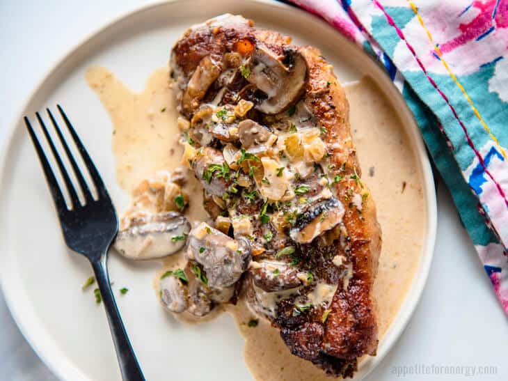 Keto Skillet Strip Steak with Mushroom Sauce on a white plate with fork