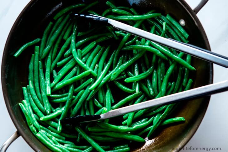 Sautéed Green Beans in a skillet with tongs