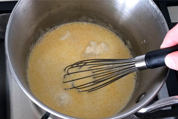 Whisking chicken broth, cream and cream cheese until smooth in a stainless steel saucepan