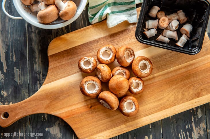 Baby portabello mushrooms on a wooden board with stems removed