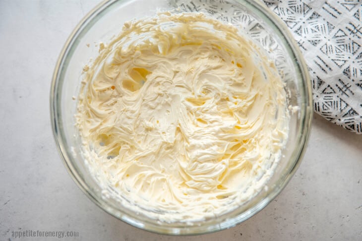 Cheesecake ingredients beaten in a glass bowl: cream, cream cheese, sweetener, vanilla extract