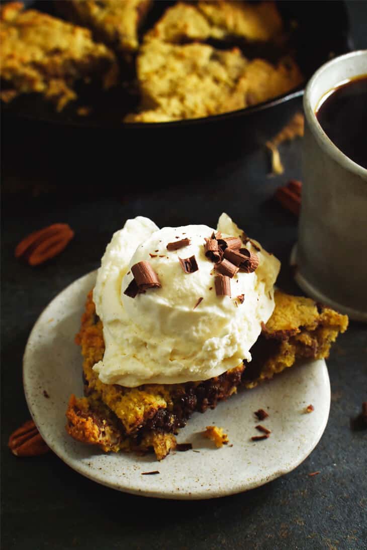 slice of skillet Chocolate-Chip-Cookie with a huge dollop of whipped cream on top