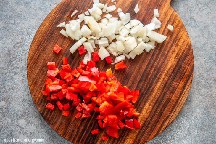 Diced peppers and onion on a round wooden board