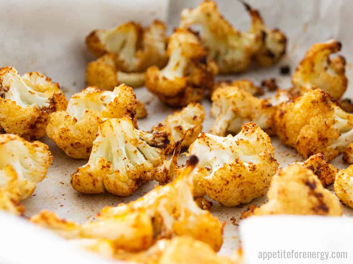 Close up of golden brown, spicy roasted cauliflower in a baking tray