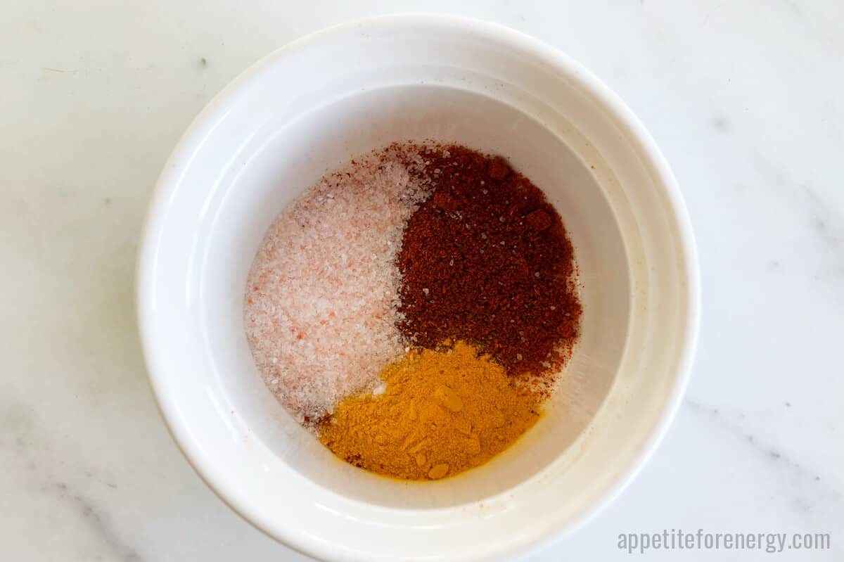 Spices - paprika, turmeric with salt in white bowl